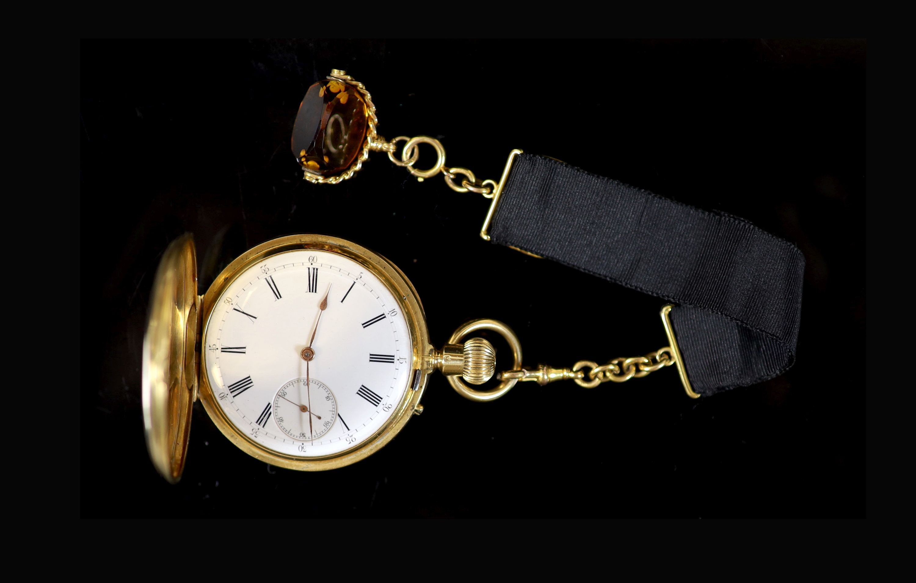 An 18ct gold full hunter keyless lever pocket watch, having white enamel Roman dial with subsidiary seconds dial, engraved monogram, on a 9ct mounted black silk ribbon, with 9ct and amber swivelling fob